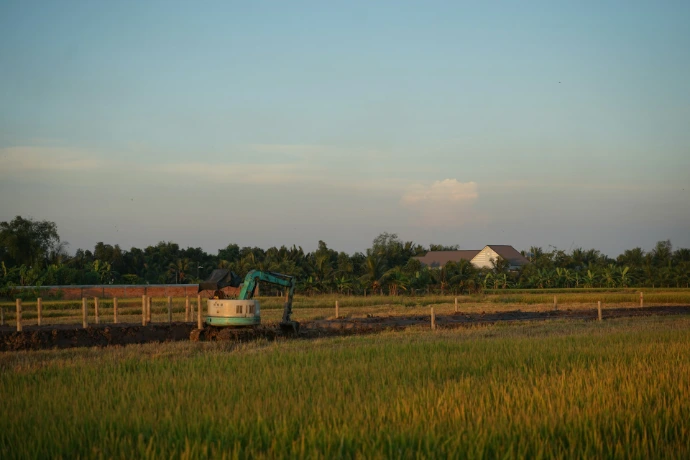 Excavator working in a rural field at sunset